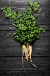 Photo of Tasty fresh ripe parsnips on black wooden table, flat lay