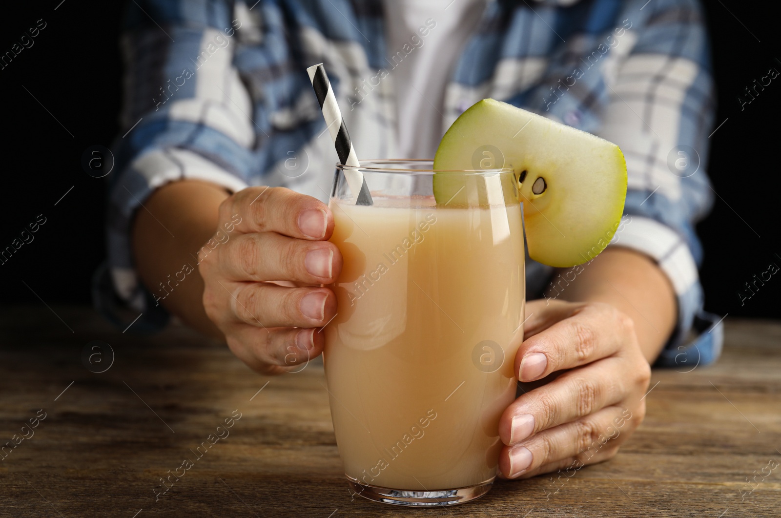 Photo of Woman with tasty pear juice at wooden table, closeup