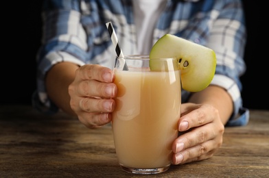 Woman with tasty pear juice at wooden table, closeup