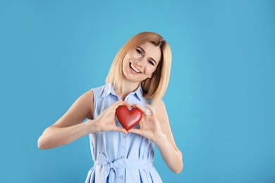 Photo of Portrait of beautiful woman holding decorative heart on color background