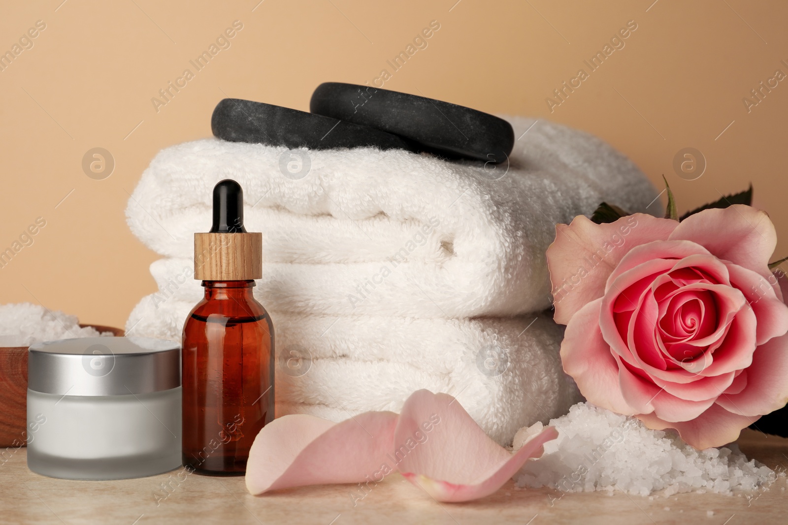 Photo of Composition with different spa products and rose on beige table