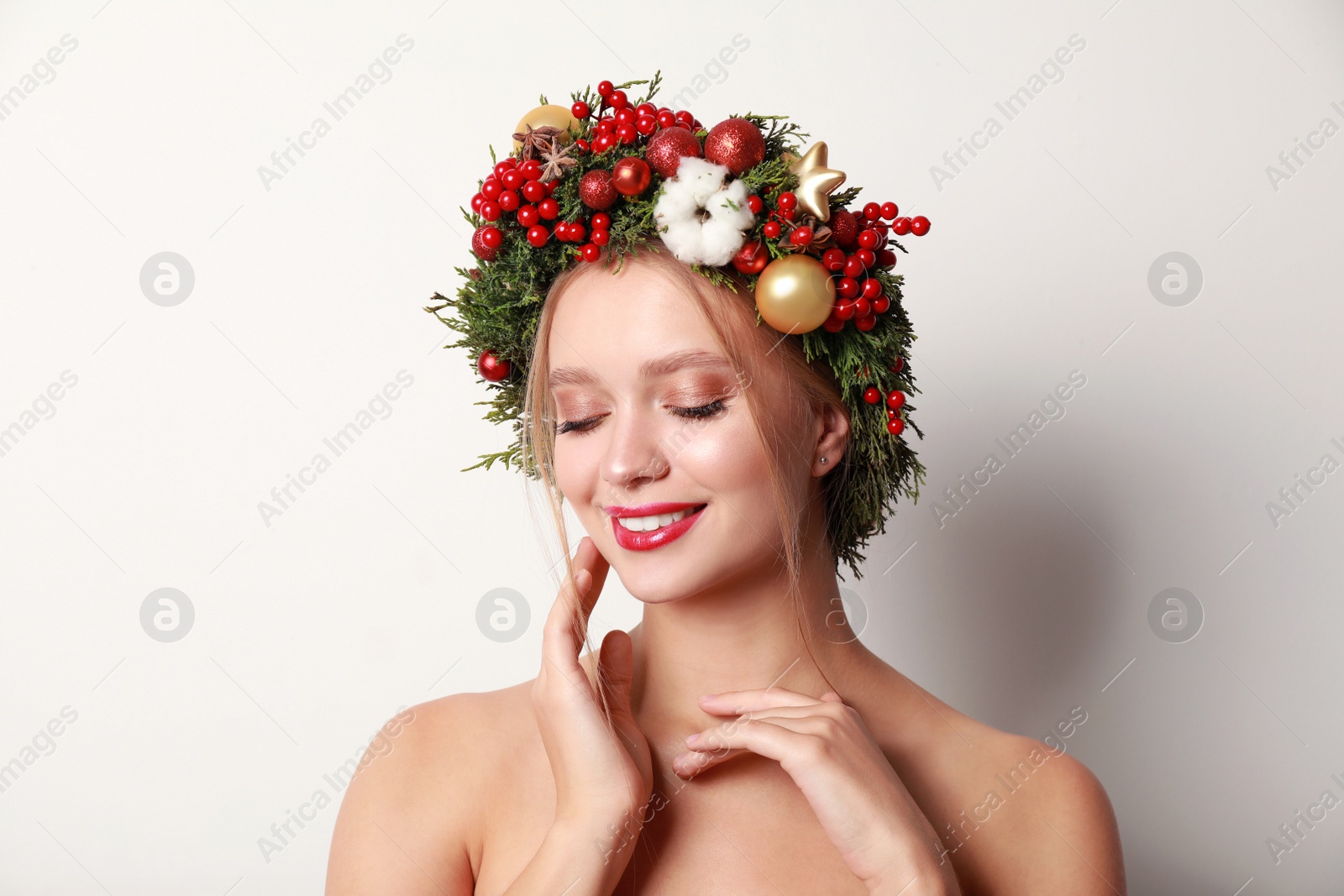 Photo of Beautiful young woman wearing Christmas wreath on white background