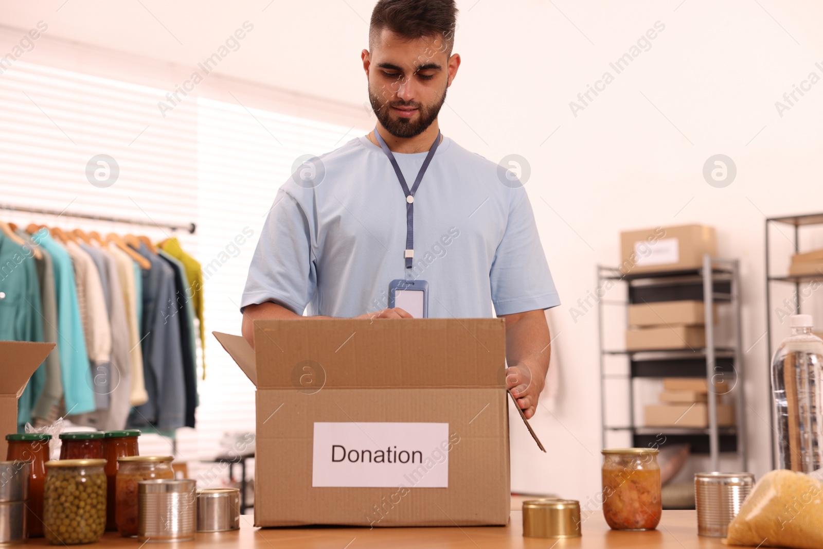 Photo of Volunteer packing food products at table in warehouse