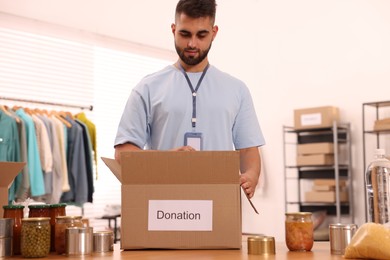 Volunteer packing food products at table in warehouse