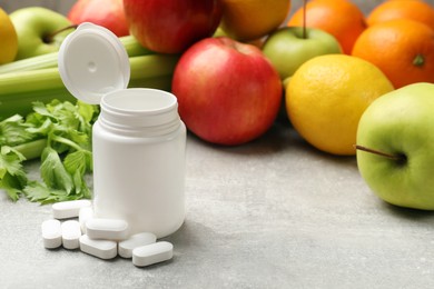 Photo of Dietary supplements. Blank white bottle and pills near food products on grey textured table