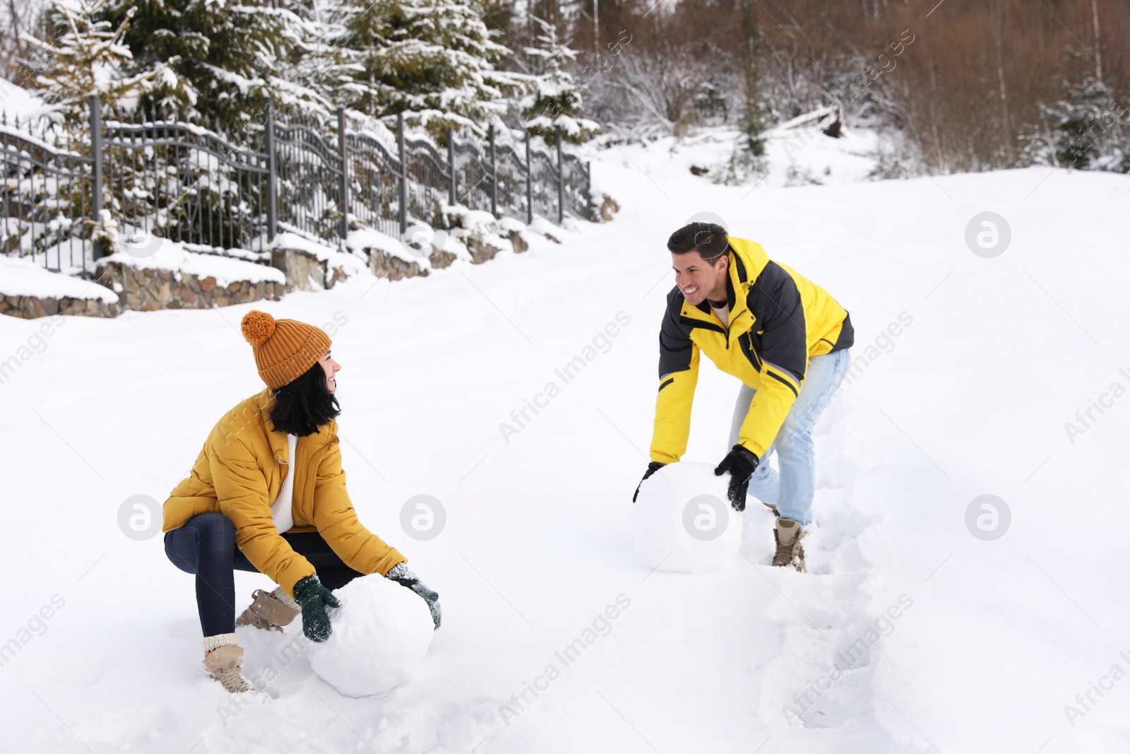 Photo of Happy couple making snowman outdoors. Winter vacation