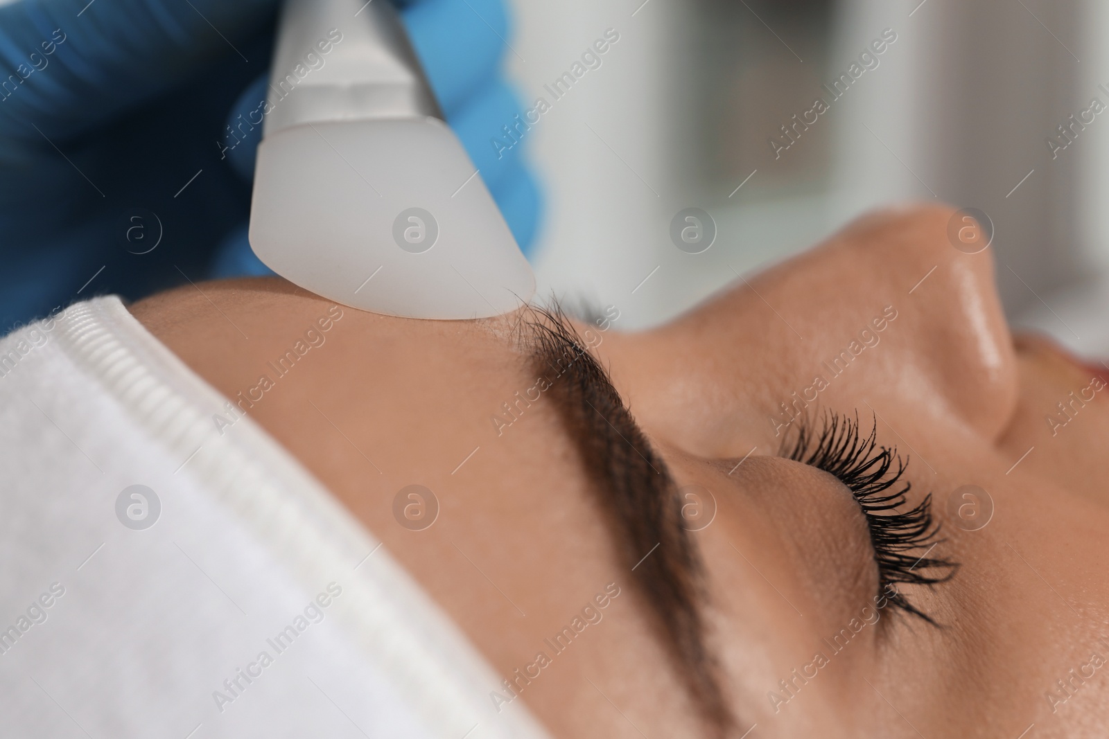 Photo of Young woman during face peeling procedure in salon, closeup