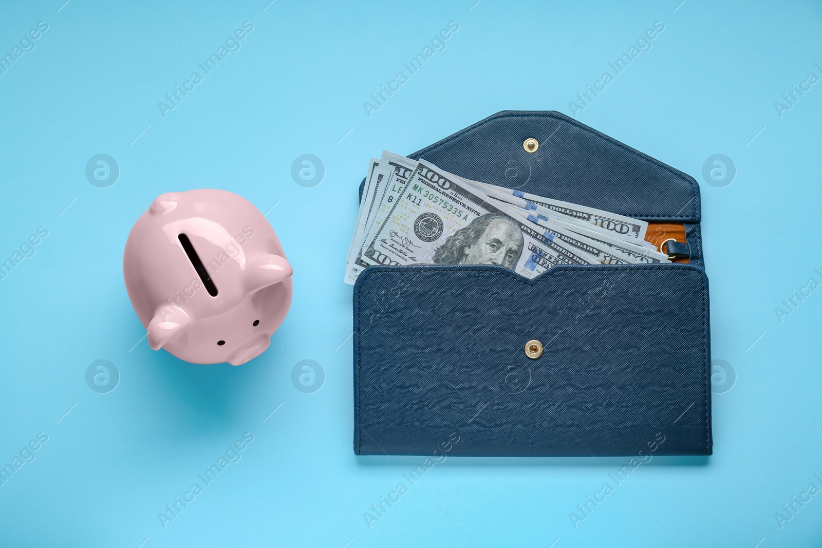 Photo of Piggy bank and wallet with banknotes on light blue background, flat lay