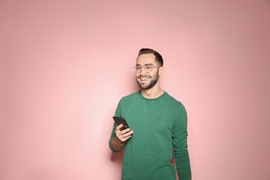 Photo of Handsome young man with mobile phone on color background
