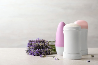 Different female deodorants and lavender flowers on marble background. Space for text