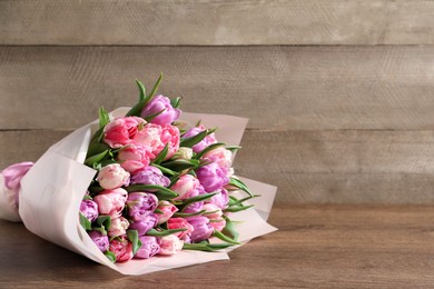 Photo of Bouquet of beautiful tulips on wooden table. Space for text