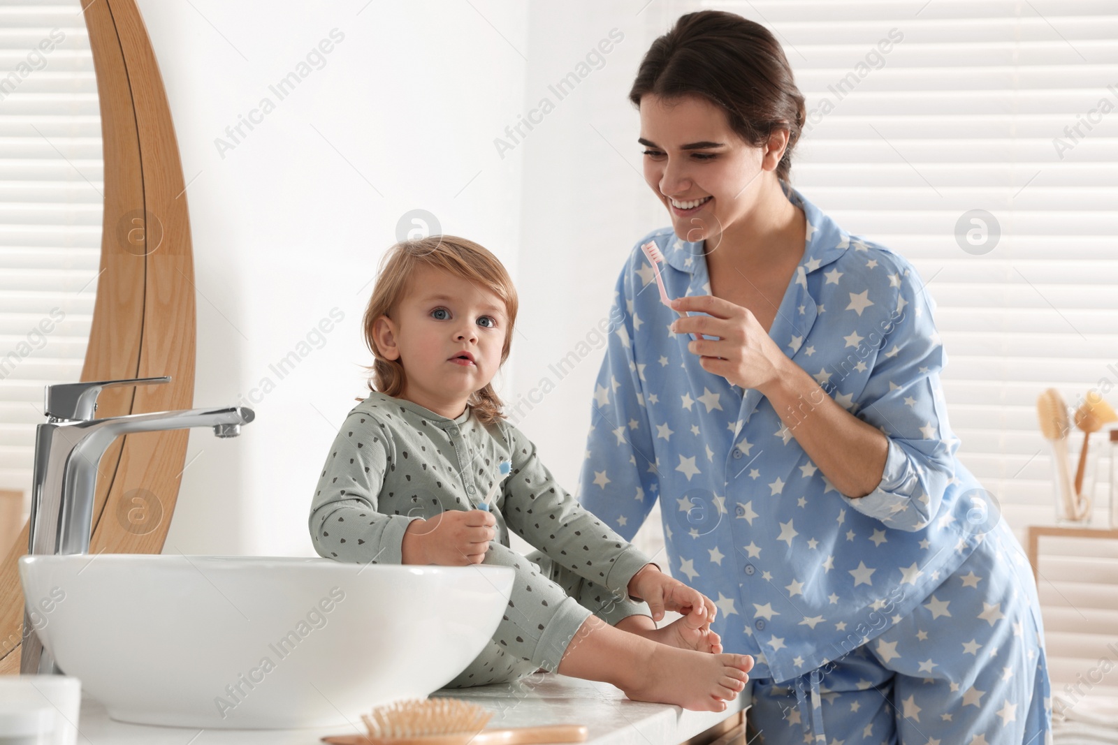 Photo of Mother and her daughter brushing teeth together in bathroom