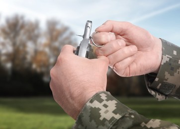 Image of Soldier pulling safety pin out of hand grenade outdoors, closeup