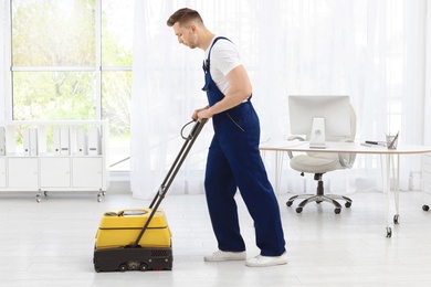 Photo of Male worker with floor cleaning machine indoors
