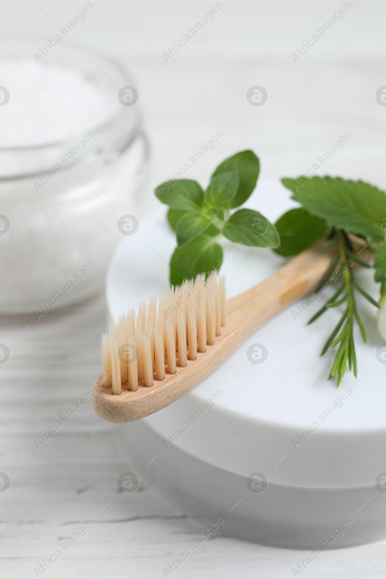 Photo of Toothbrush, dental products and herbs on white wooden table, closeup