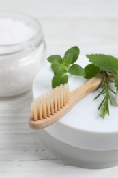 Photo of Toothbrush, dental products and herbs on white wooden table, closeup