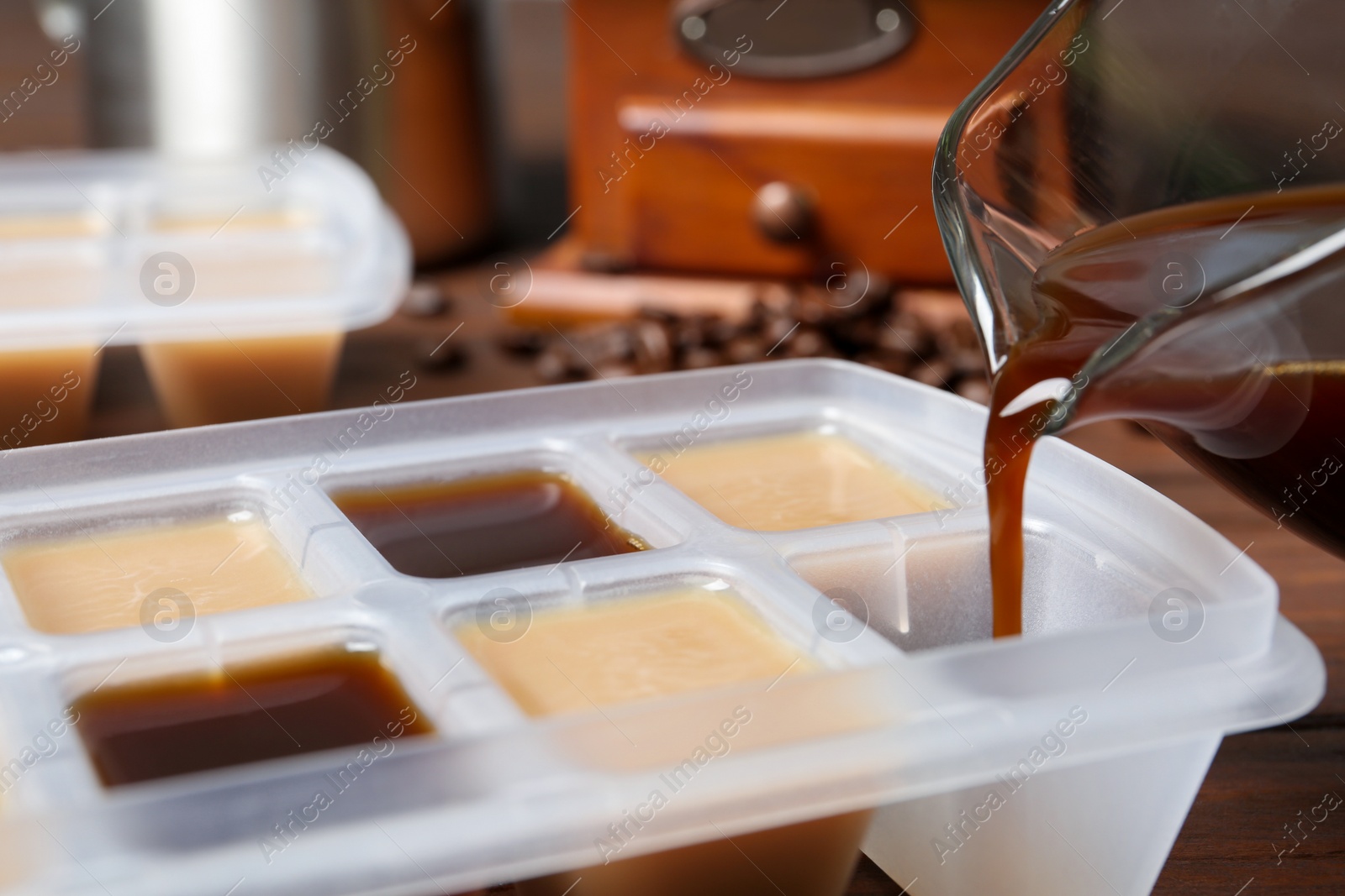 Photo of Pouring coffee in ice cube tray on table, closeup