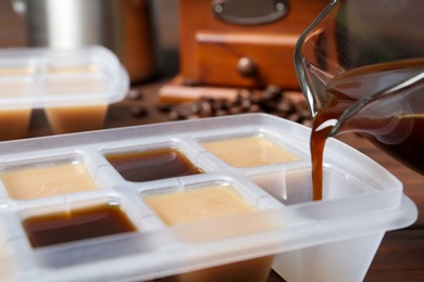 Pouring coffee in ice cube tray on table, closeup