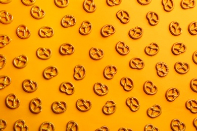 Delicious pretzel crackers on orange background, flat lay