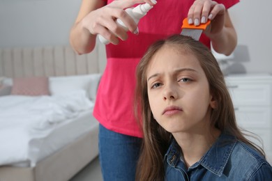 Photo of Mother using nit comb and spray on daughter's hair at home. Anti lice treatment