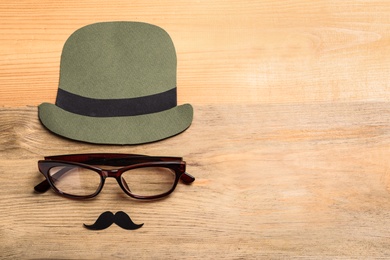 Photo of Flat lay composition with glasses, paper hat and mustaches on wooden background. Father's day celebration