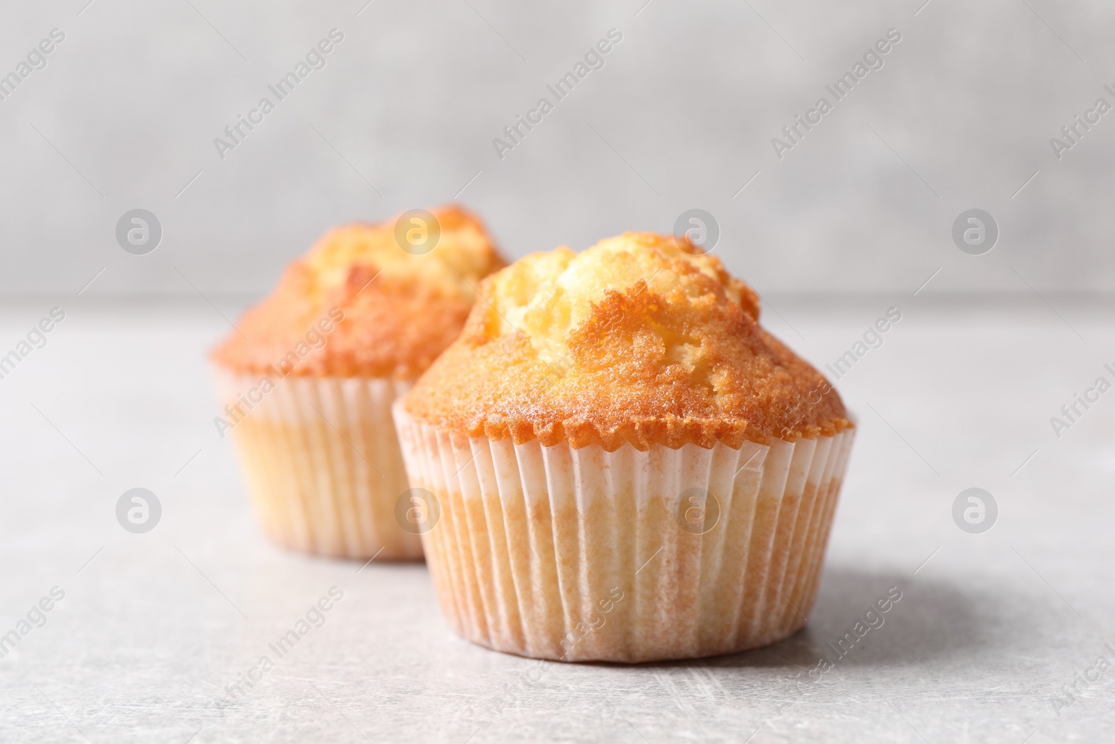 Photo of Tasty muffins on light grey table, closeup. Fresh pastry