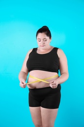 Fat woman with measuring tape on color background. Weight loss