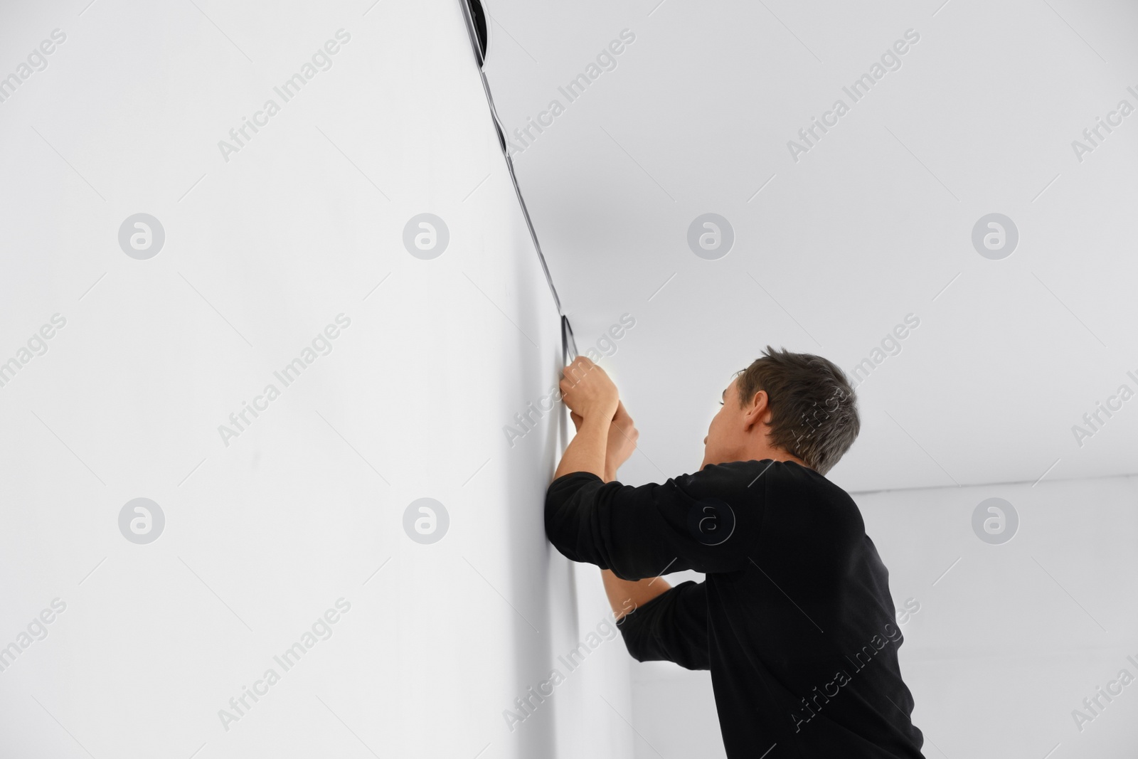 Photo of Repairman installing white stretch ceiling in room