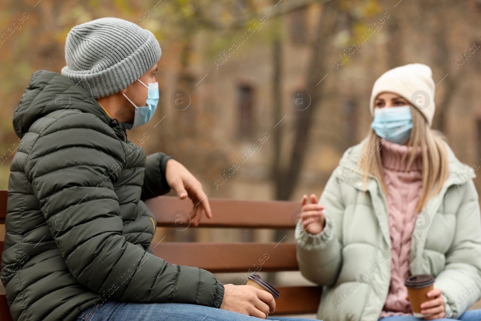 Photo of People in medical masks keeping distance while talking outdoors. Protective measures during coronavirus quarantine