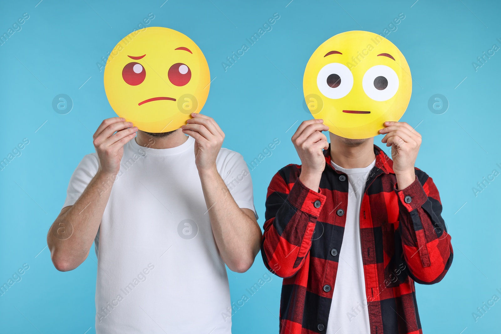 Photo of People covering faces with emoticons on light blue background