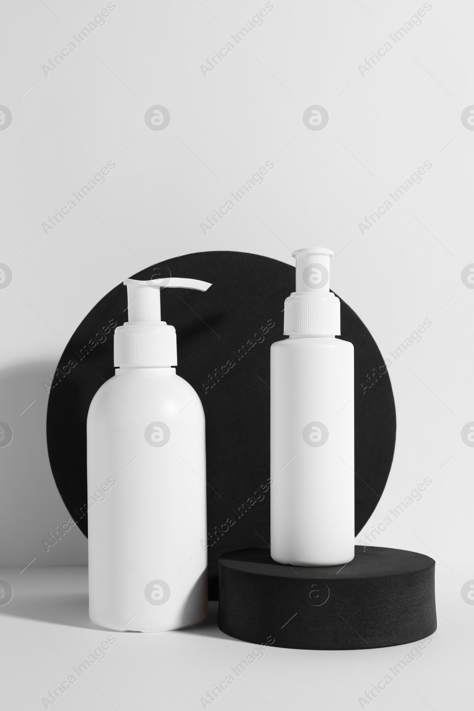 Photo of Bottles with different cosmetic products and podiums on white background