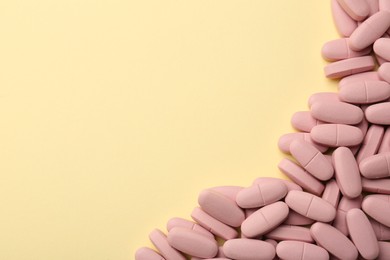 Vitamin pills on pale yellow background, top view. Space for text