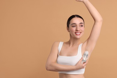 Photo of Beautiful woman applying deodorant on beige background, space for text