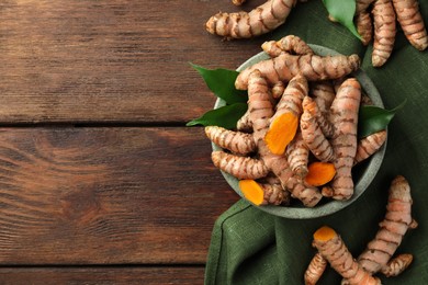 Fresh turmeric roots on wooden table, flat lay. Space for text