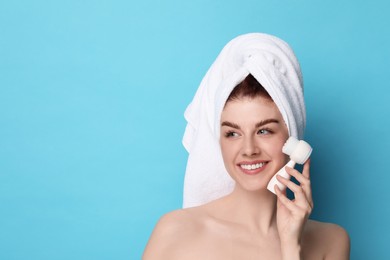 Photo of Washing face. Young woman with cleansing brush on light blue background, space for text