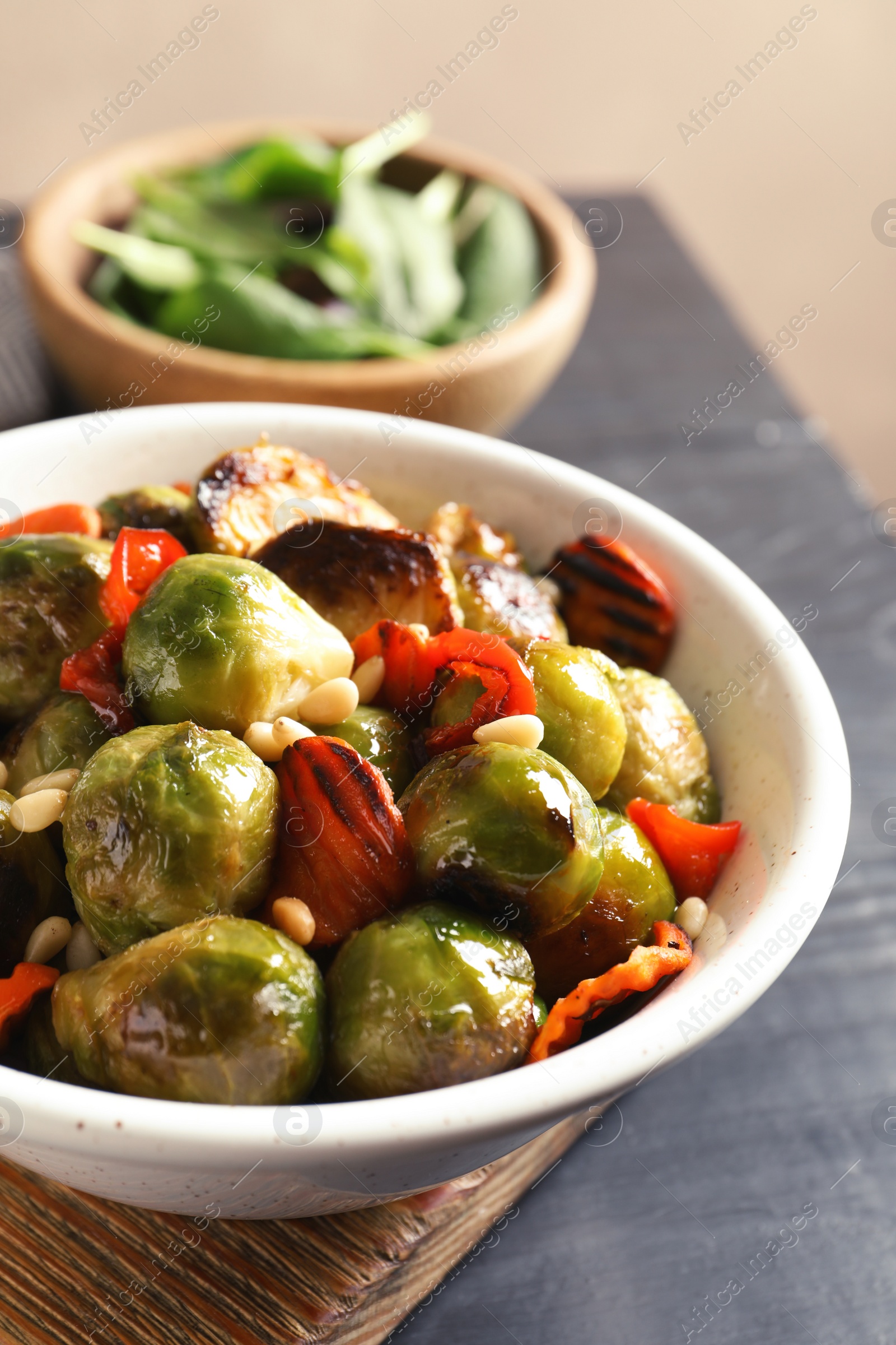 Photo of Bowl of warm salad with Brussels sprouts and carrots on table