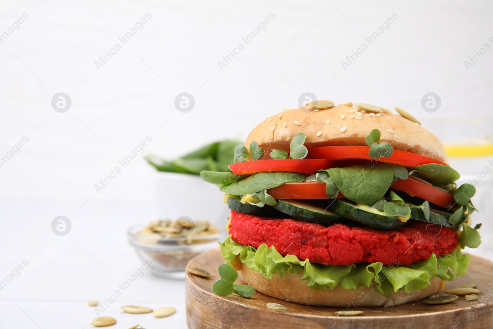 Photo of Tasty vegan burger with vegetables, patty and microgreens on white tiled table, closeup. Space for text