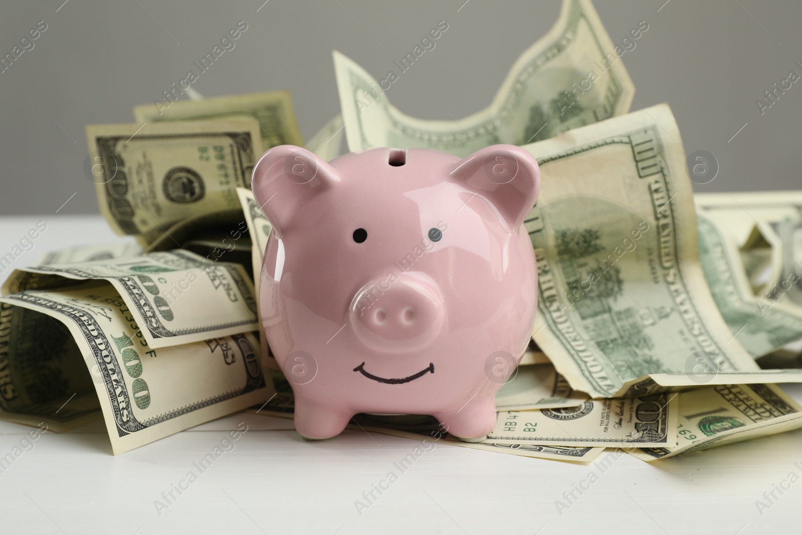 Photo of Money exchange. Dollar banknotes and piggy bank on white wooden background, closeup
