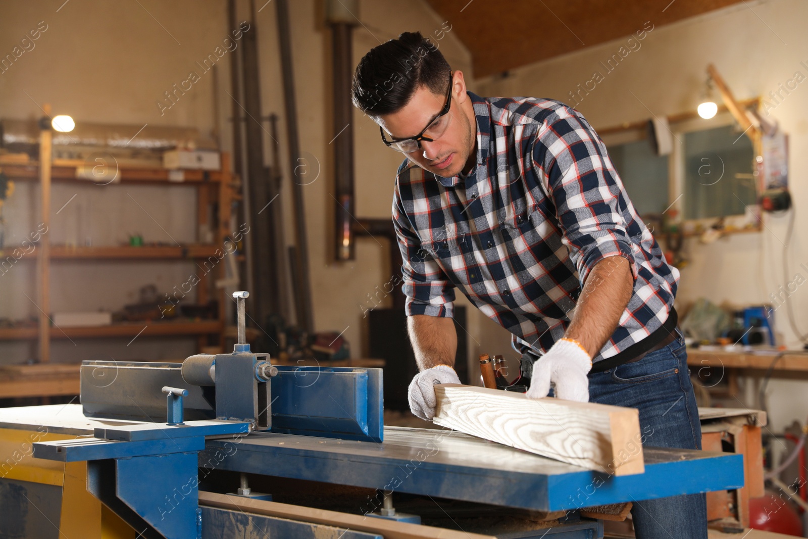 Photo of Professional carpenter working with wooden plank in workshop