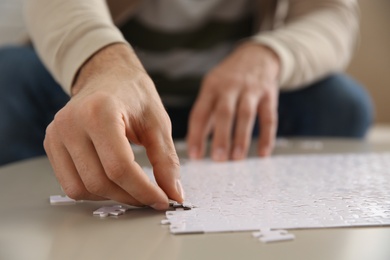 Photo of Man playing with puzzles at table, closeup