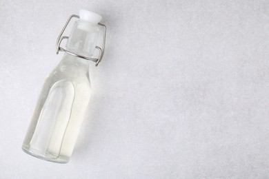 Photo of Vinegar in glass bottle on light table, top view. Space for text