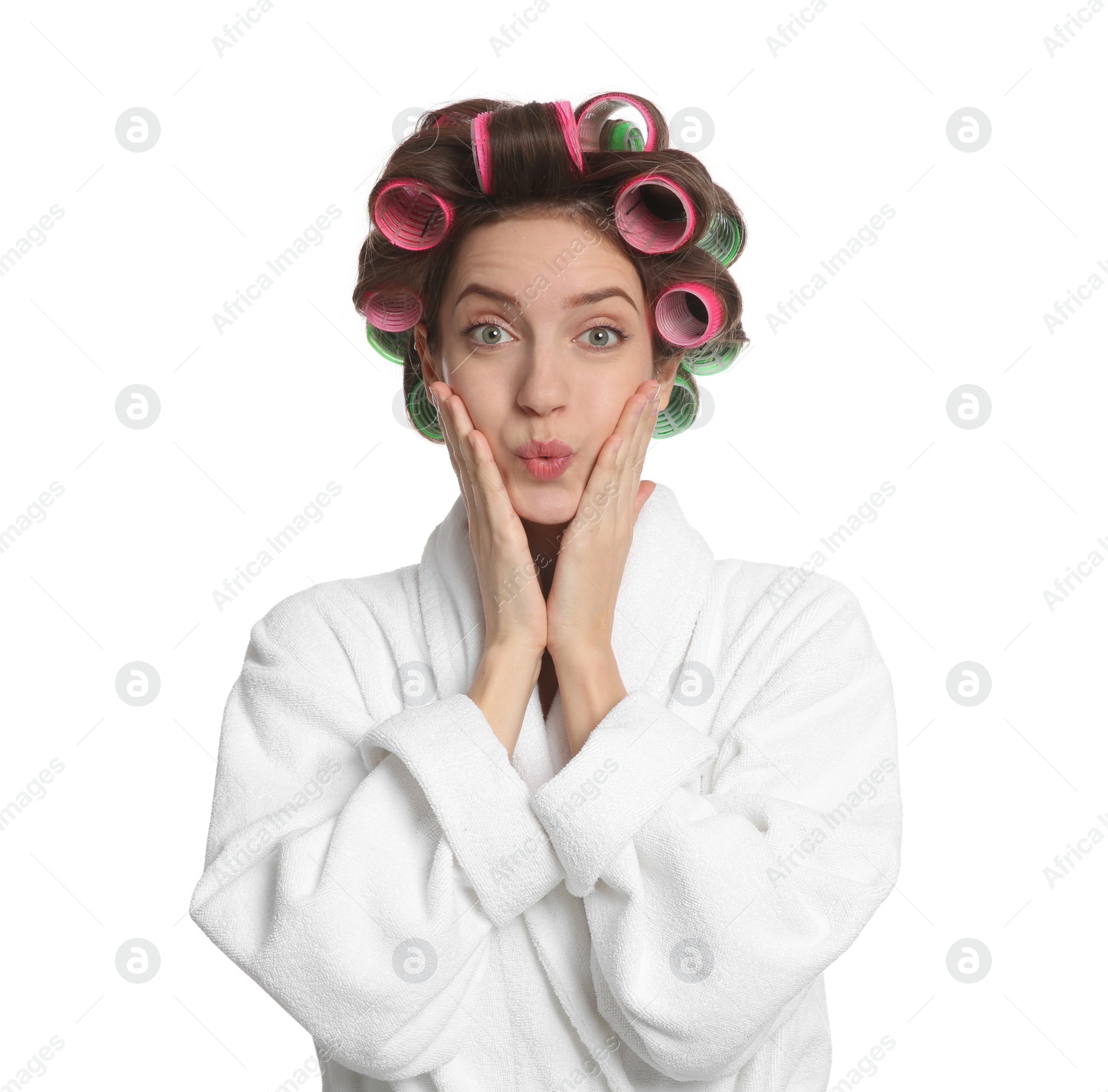 Photo of Emotional young woman in bathrobe with hair curlers on white background