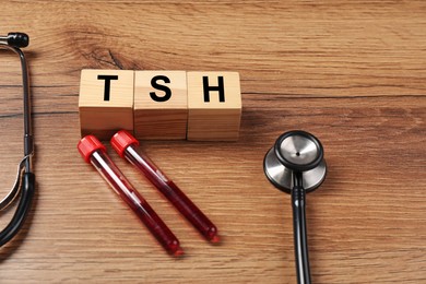 Photo of Endocrinology. Stethoscope, cubes with thyroid hormones and blood samples in test tubes on wooden table