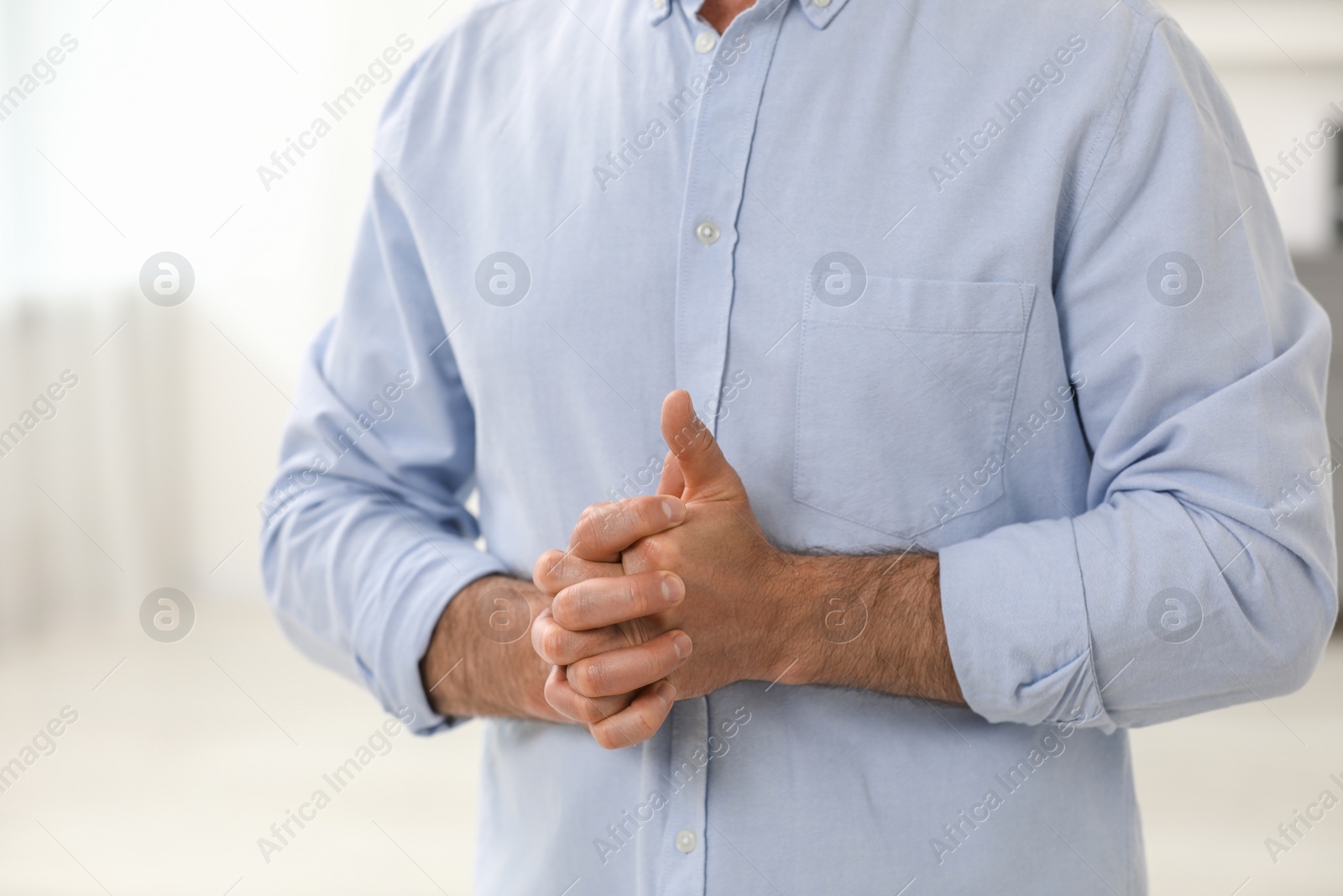 Photo of Man cracking his knuckles on blurred background, closeup. Bad habit