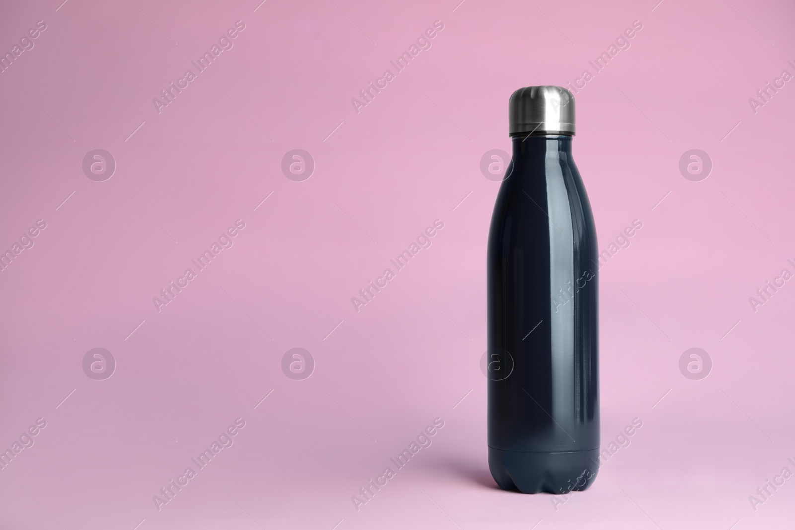 Photo of Stylish thermo bottle on pink background, space for text