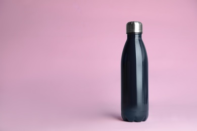 Stylish thermo bottle on pink background, space for text