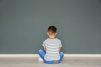 Lonely little boy sitting on floor in room. Autism concept