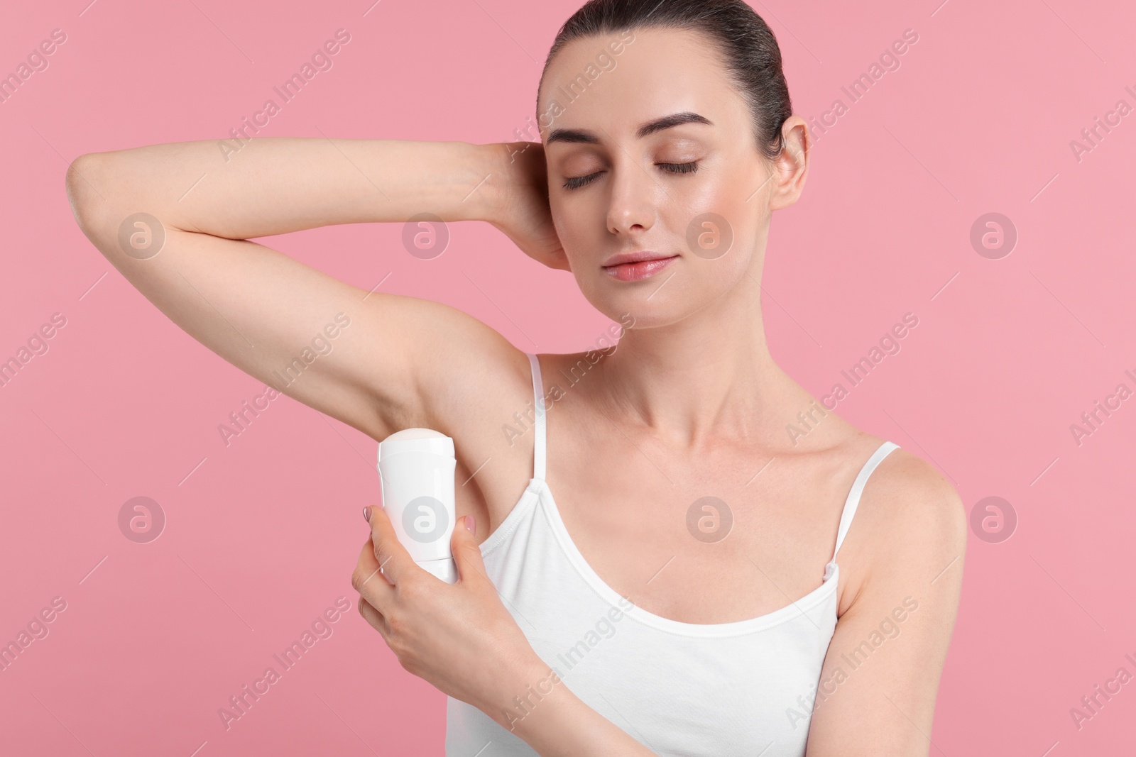 Photo of Beautiful woman applying deodorant on pink background