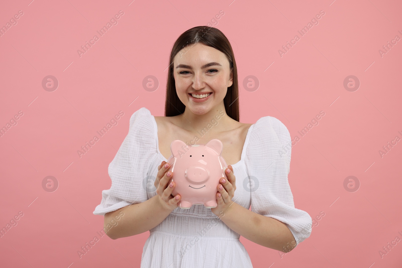 Photo of Happy woman with piggy bank on pink background