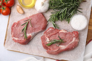 Photo of Fresh raw meat with rosemary and spices on light table, flat lay